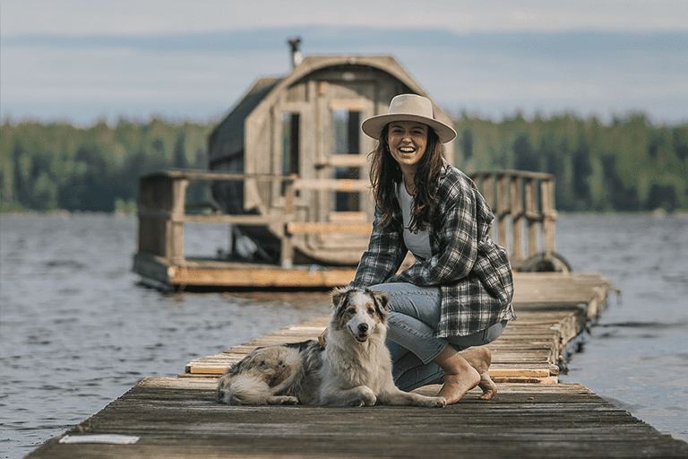 Vrouw met een hond voor de sauna op het meer